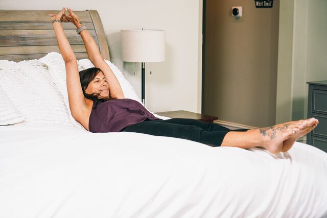 Woman stretching on bed to alleviate restless legs syndrome (RLS) 